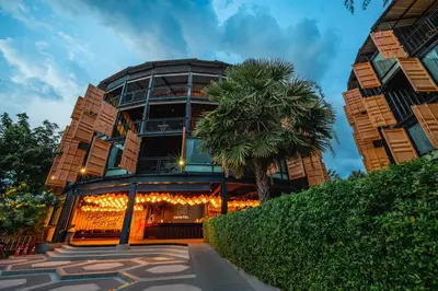 a building with a palm tree in front of it at Hivetel Phuket in Chalong