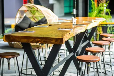 a large wooden table with stools around it at Hivetel Phuket in Chalong