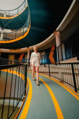 a woman walking down a hallway in a building at Hivetel Phuket in Chalong