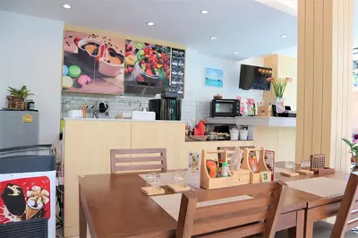 a dining room with a table and a kitchen at iNest Poshtel in Kata Beach