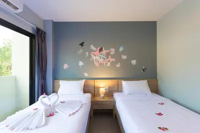 two beds in a room with butterflies on the wall at iNest Poshtel in Kata Beach