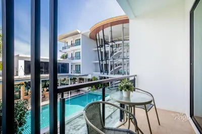 a balcony with a table and chairs and a swimming pool at The Pago Design Hotel Phuket-SHA Plus in Phuket Town