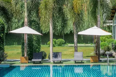 two chairs and two umbrellas next to a swimming pool at The Pago Design Hotel Phuket-SHA Plus in Phuket Town