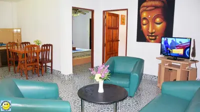a living room with chairs and a table with a tv at D&K Smiley Phuket Resort in Rawai Beach