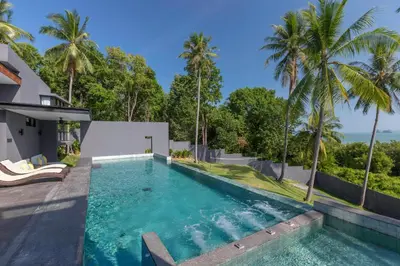 an infinity pool in the backyard of a house with palm trees at Braya Villa in Ko Yao Yai