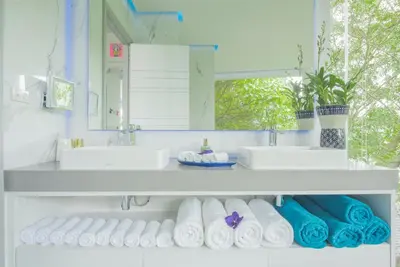 a bathroom with two sinks and towels on a shelf at Villa Enjoy Phuket in Patong Beach