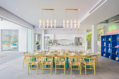 a dining room with a wooden table and yellow chairs at Villa Enjoy Phuket in Patong Beach