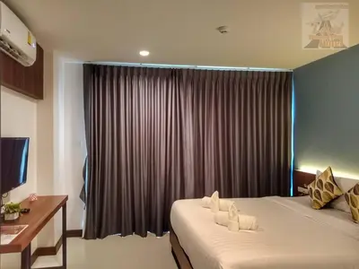a bedroom with two beds and a window with curtains at Louis' Runway View Hotel - SHA Extra Plus in Nai Yang Beach