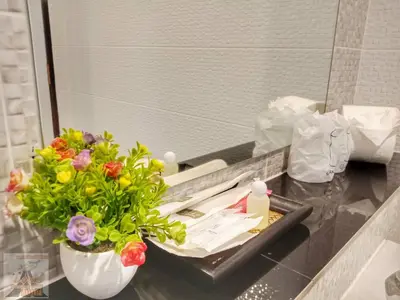 a bathroom counter with a vase of flowers and a mirror at Louis' Runway View Hotel - SHA Extra Plus in Nai Yang Beach