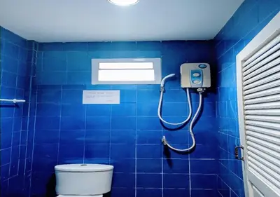 a blue tiled bathroom with a shower and a toilet at Golden Bee PhiPhi in Phi Phi Don