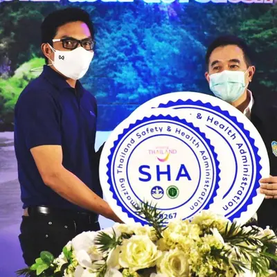 two men wearing masks holding a sign with flowers at Golden Bee PhiPhi in Phi Phi Don