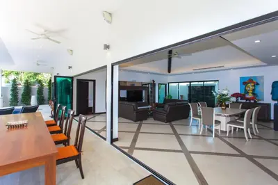 a dining room and living room with sliding glass doors at Spacious 4 Bedrooms Private Pool Villa in Phuket in Rawai Beach
