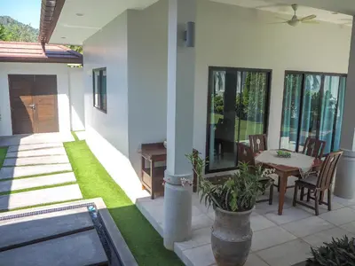 a house with a patio with a table and chairs at Spacious 4 Bedrooms Private Pool Villa in Phuket in Rawai Beach