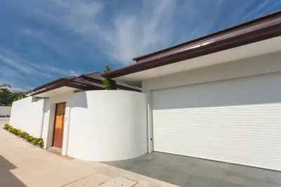 a garage with white doors on a house at Spacious 4 Bedrooms Private Pool Villa in Phuket in Rawai Beach
