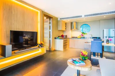 a living room with a large television and a kitchen at The Senses Resort & Pool Villas, PHUKET in Patong Beach