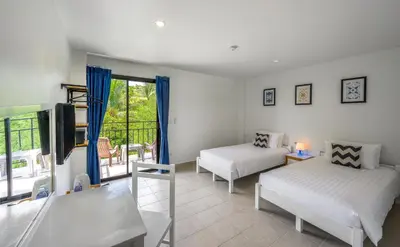 a living room with two beds and a window at Maikhao Hotel, Phuket in Mai Khao Beach