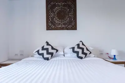 a white bed with black and white pillows on it at Maikhao Hotel, Phuket in Mai Khao Beach