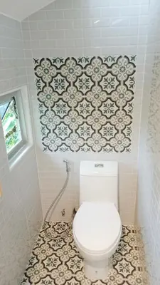 a white toilet in a bathroom with a tile wall at Nua Tone Resort Bang Tao & Cafe in Bang Tao Beach