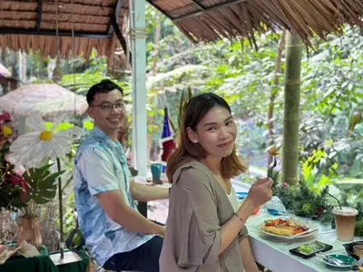 a man and a woman sitting at a table eating food at Nua Tone Resort Bang Tao & Cafe in Bang Tao Beach