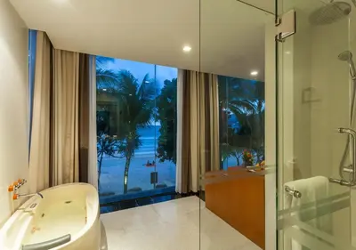 a bathroom with a tub and a shower and a window at La Flora Resort Patong in Patong Beach