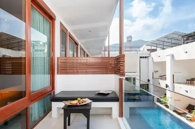 a balcony with a table and a pool at La Flora Resort Patong in Patong Beach