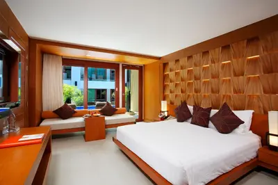 a bedroom with a large bed and a desk at La Flora Resort Patong in Patong Beach
