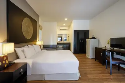 a bedroom with a large white bed and a desk at Nai Yang Beach Resort and Spa in Nai Yang Beach