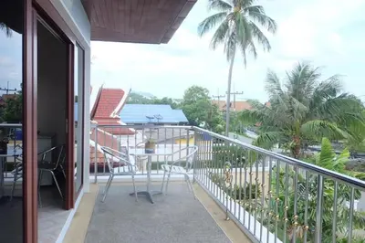 a balcony with a view of a palm tree at Majestic Villas Guesthouse Phuket. in Rawai Beach