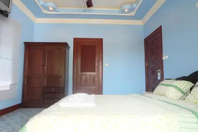 a bedroom with a large bed with a wooden headboard at Majestic Villas Guesthouse Phuket. in Rawai Beach