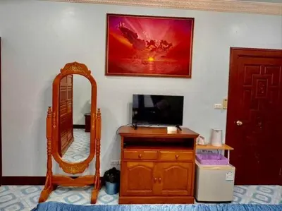 a bedroom with a mirror and a dresser with a television at Majestic Villas Guesthouse Phuket. in Rawai Beach