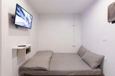 a bed in a room with a tv on a wall at Minimal House Patong in Patong Beach