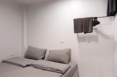 a white room with a bed with two pillows at Minimal House Patong in Patong Beach