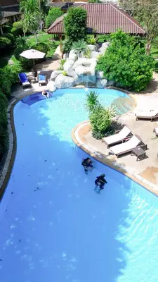 a large swimming pool with chairs and blue water at Palm Garden Resort in Rawai Beach