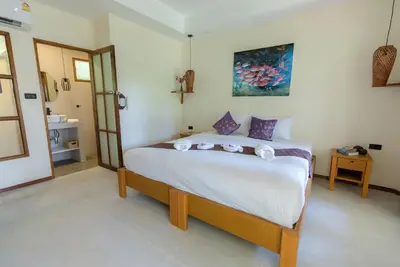 a bedroom with a large white bed with purple pillows at Palm Garden Resort in Rawai Beach