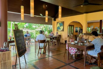 a group of people sitting at tables in a restaurant at Palm Garden Resort in Rawai Beach
