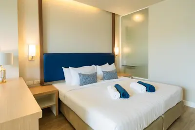 a bedroom with a large bed with blue and white pillows at Phuket Boat Quay Hotel Panwa Beach in Panwa Beach