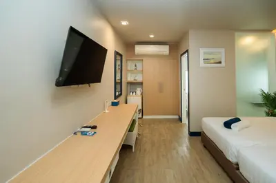 a room with a desk and a tv on a wall at Phuket Boat Quay Hotel Panwa Beach in Panwa Beach