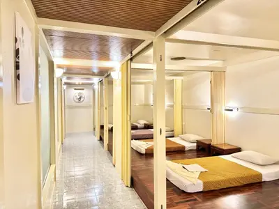 a row of beds in a room with wooden floors at Phuket Merlin Hotel in Phuket Town