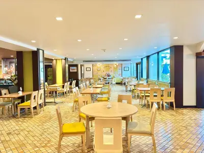 a restaurant with wooden tables and chairs and tables and chairs at Phuket Merlin Hotel in Phuket Town