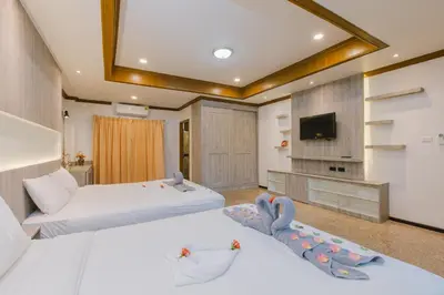 a hotel room with two beds and a flat screen tv at Royal Prince Residence, Patong Beach in Patong Beach