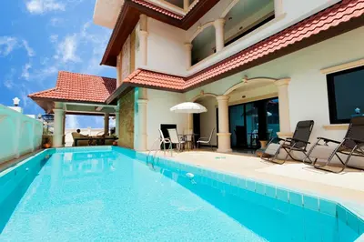 a swimming pool with chairs and a house at Royal Prince Residence, Patong Beach in Patong Beach