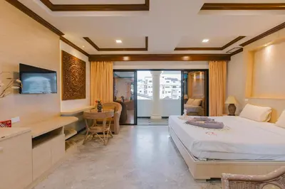 a bedroom with a bed and a desk and a kitchen at Royal Prince Residence, Patong Beach in Patong Beach
