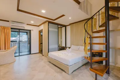 a bedroom with a bed and a spiral staircase at Royal Prince Residence, Patong Beach in Patong Beach