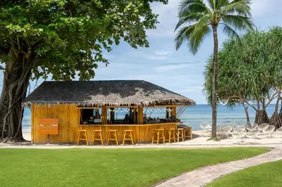 a restaurant on the beach with chairs and palm trees at Phuket Marriott Resort & Spa, Merlin Beach in Patong Beach