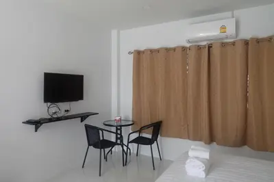 a room with a table and two chairs and a television at Airport Pearl Residence in Nai Yang Beach