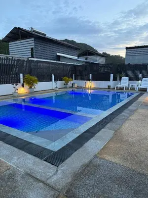 a swimming pool with white chairs and a blue pool at EX-IT Inn in Patong Beach