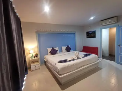 a bedroom with a large bed with a blue headboard at Phuket Racha Kata Homestay in Kata Beach