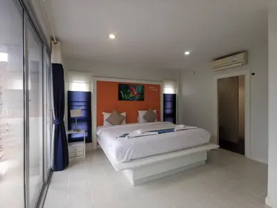 a bedroom with a large bed with an orange headboard at Phuket Racha Kata Homestay in Kata Beach