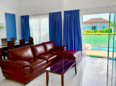 a living room with a leather couch and blue curtains at Villa Bang Tao 3 Bedroom Q Kata Residence in Bang Tao Beach