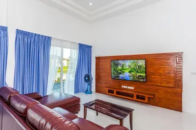 a living room with a leather couch and a flat screen tv at Villa Bang Tao 3 Bedroom Q Kata Residence in Bang Tao Beach